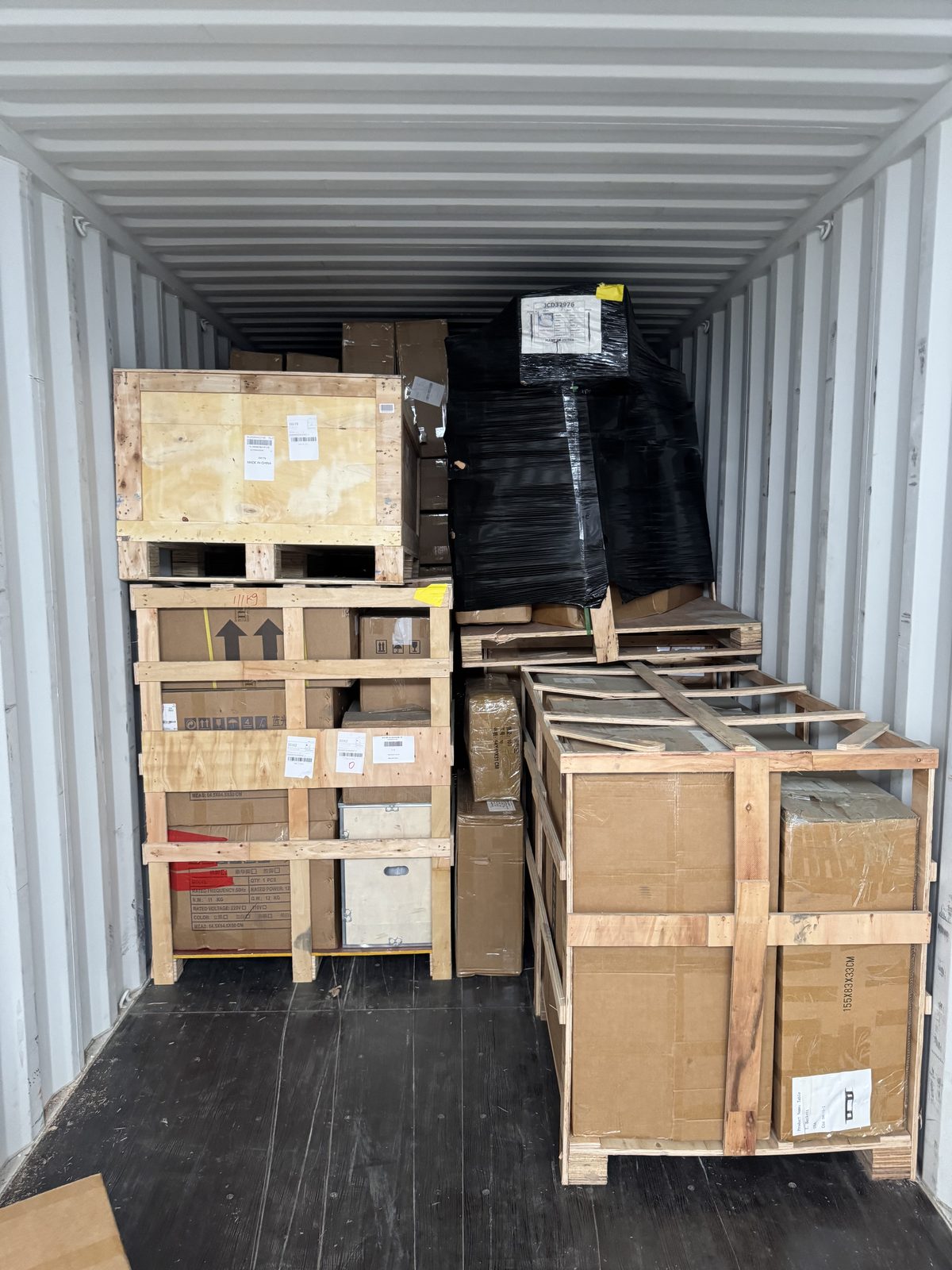Crates stacked on wooden pallets inside an ocean container during devanning