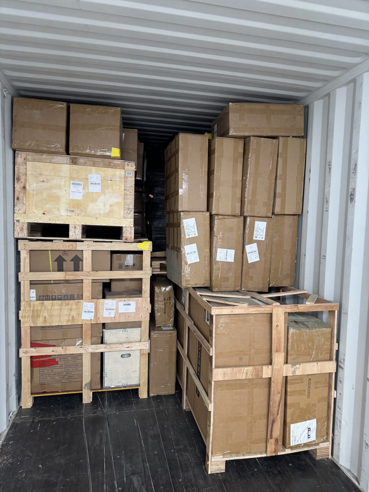 Cardboard cartons floor-loaded inside an ocean container being unloaded during devanning