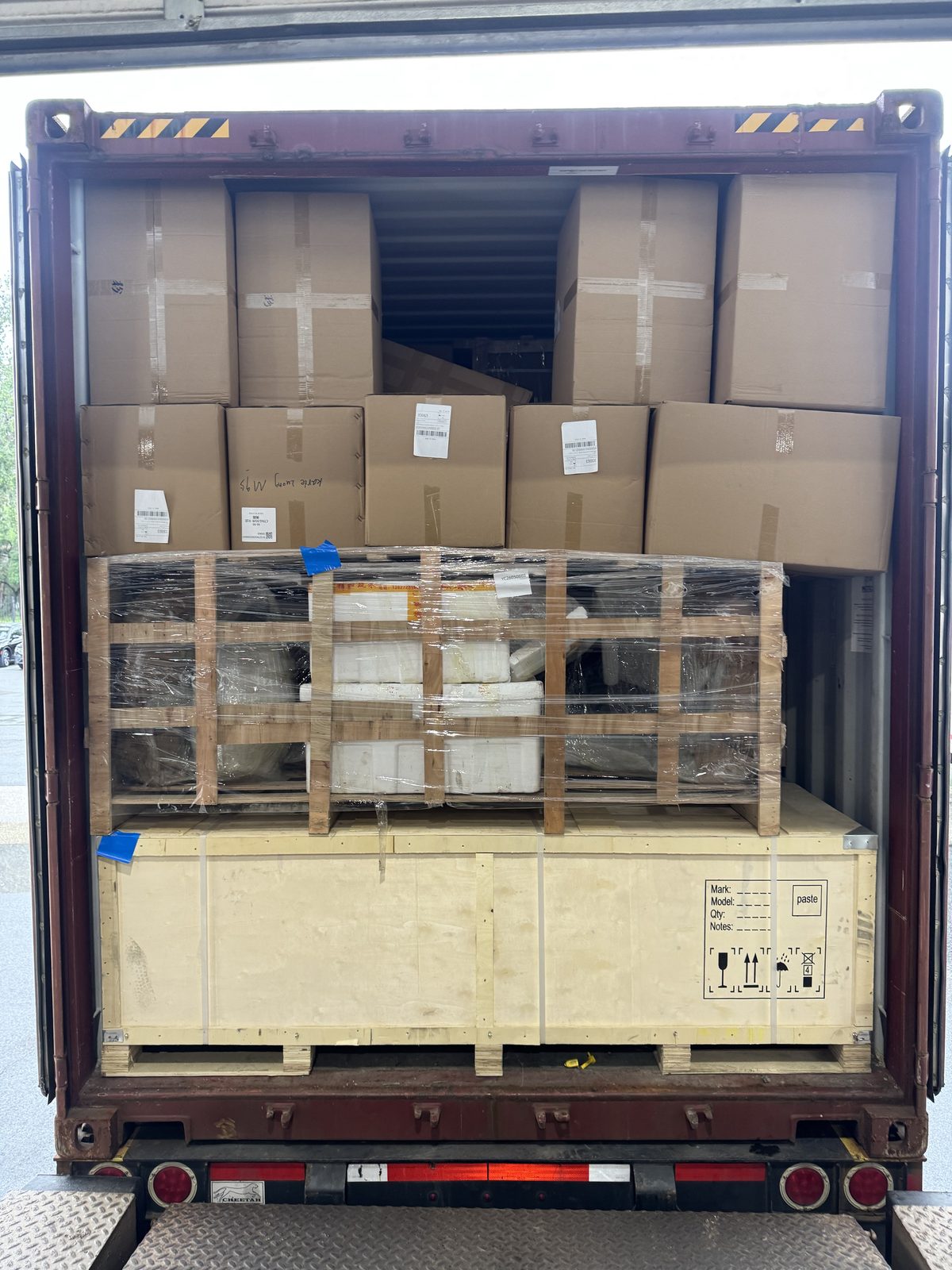 Rear view of an ocean container loaded with palletized boxes and crates at a warehouse dock