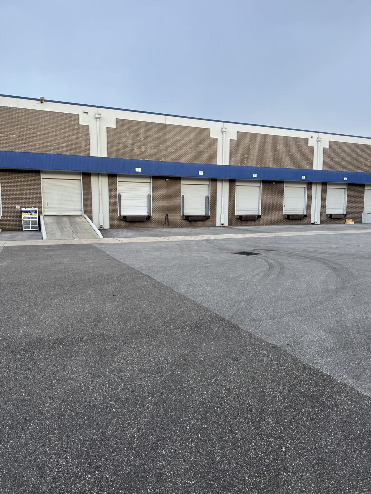 Exterior of a warehouse building showing dock doors and a loading ramp